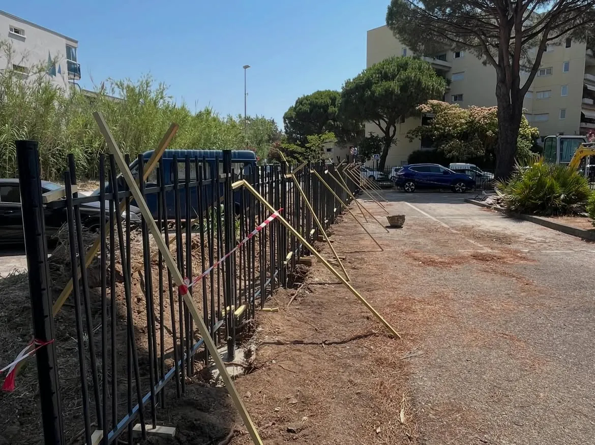 Panneaux de clôture calés par des bois pendant la pose au Lavandou